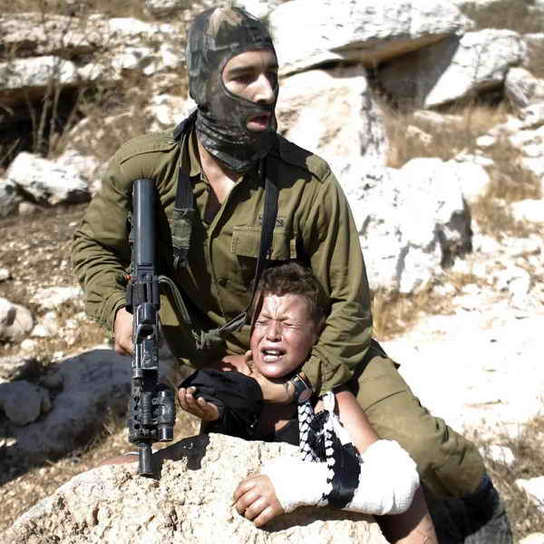 Israeli soldier abducting a Palestinian child with broken arm