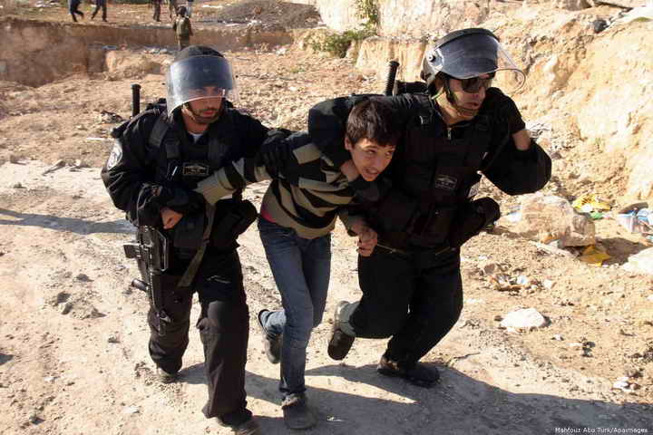 Israeli soldiers arrestin a Palestinian child in aggressive grip