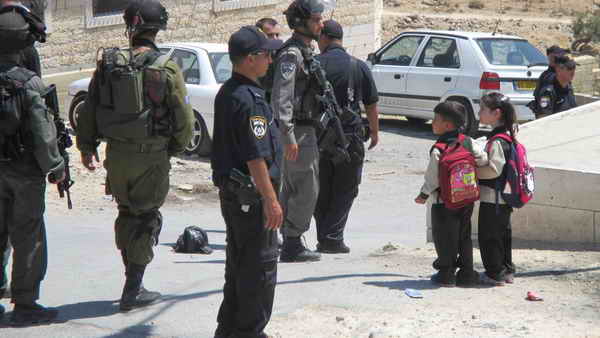 Palestinian schoolchildren acrossing Israeli soldiers